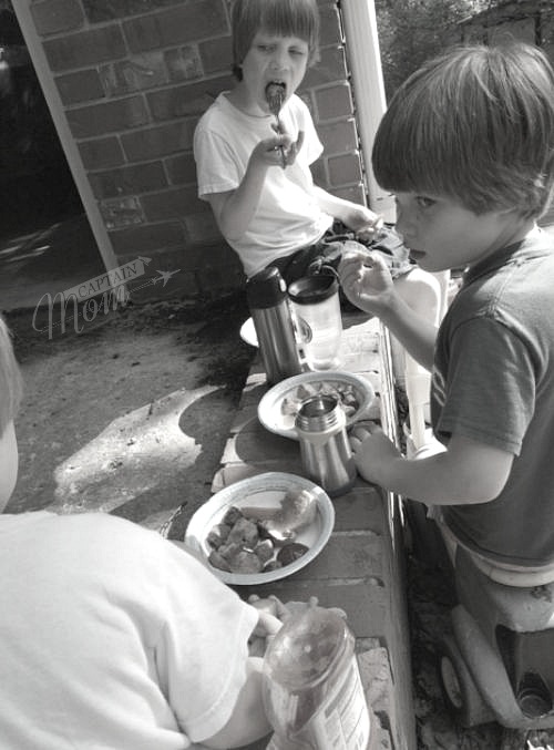 three brothers eating outside on paper plates 